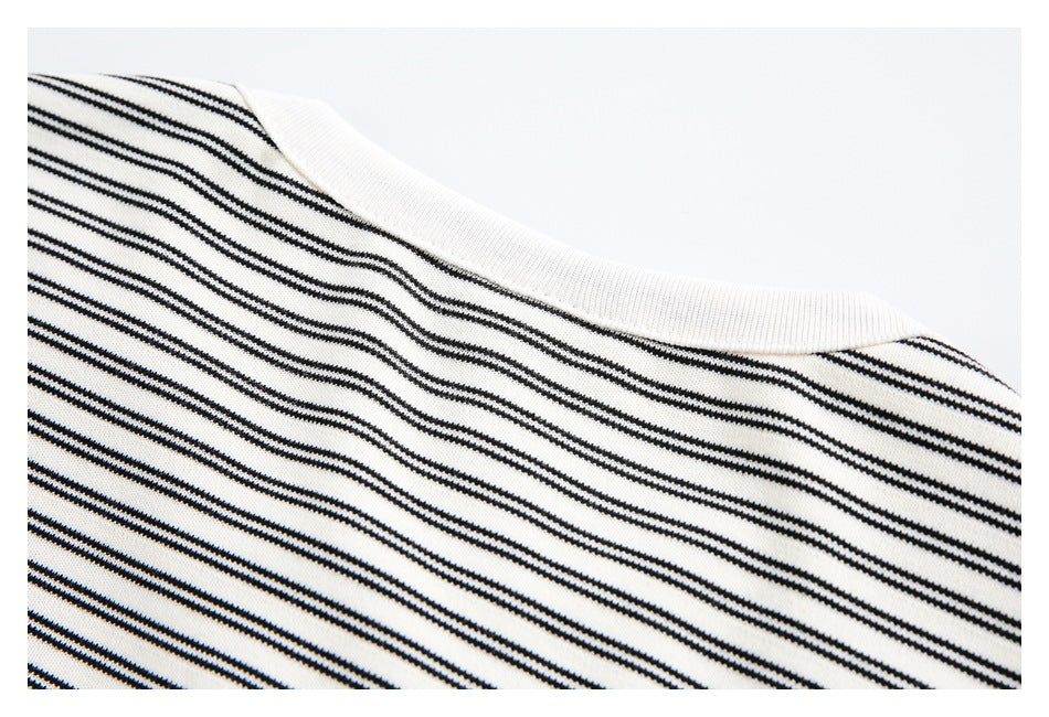 Close-up of a ribbed off-white crew neckline above thin black stripes.