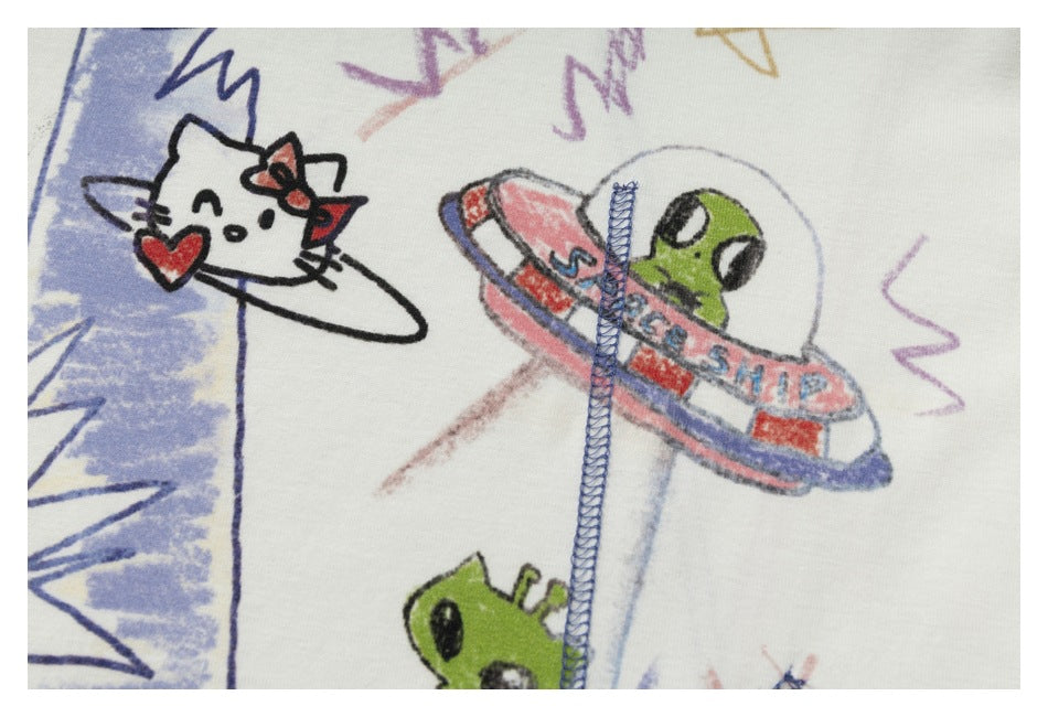 Close-up of cartoon cat and green alien illustrations on a white shirt, with blue stitching across the print.