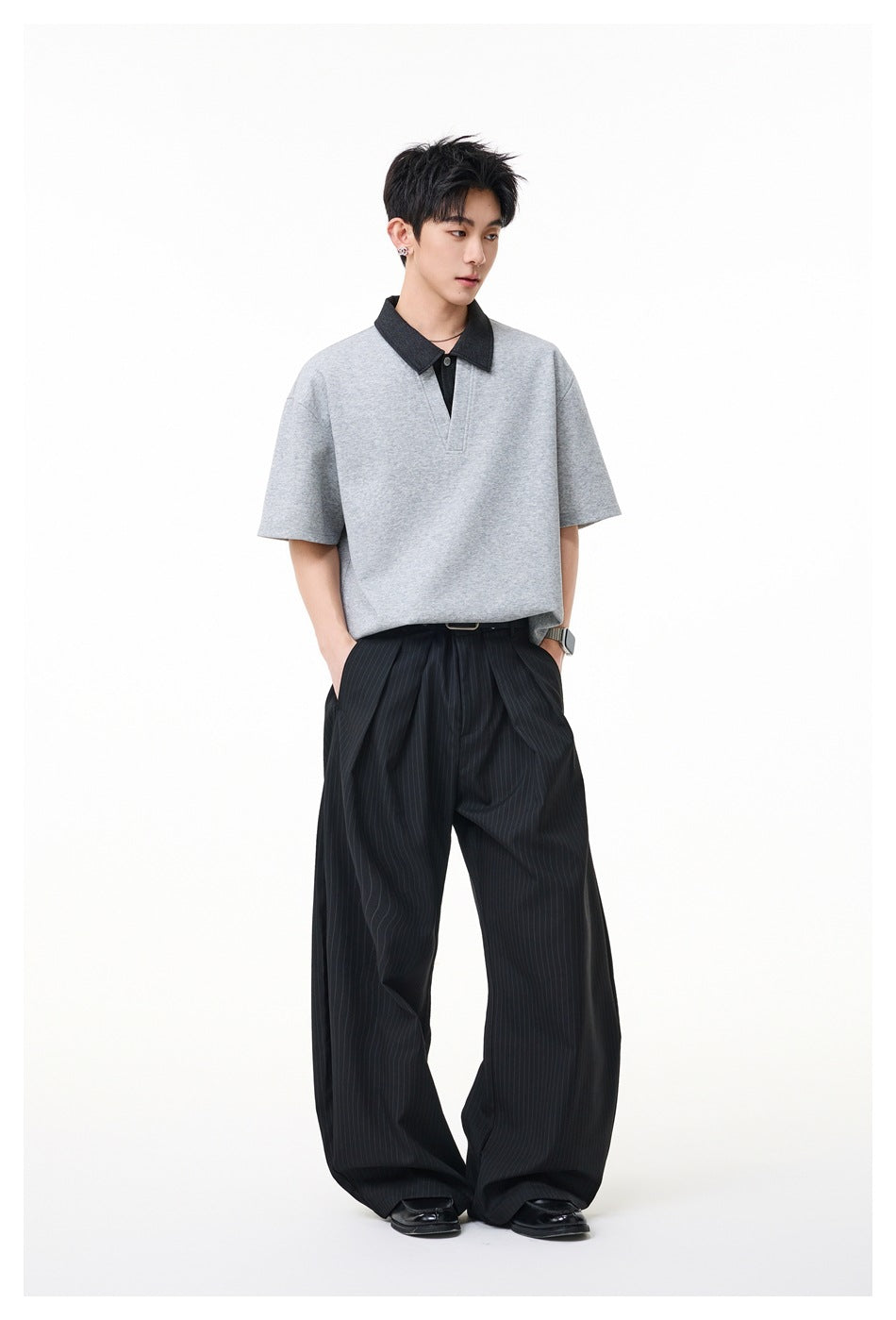 Full-length view of a model wearing a gray short-sleeve polo with a dark collar and black pinstripe trousers.