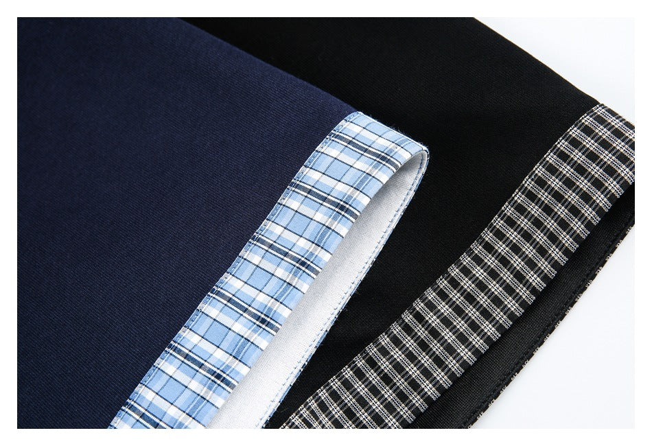 Close-up of navy and black polo shirt fabric with blue and black-and-white plaid trim.