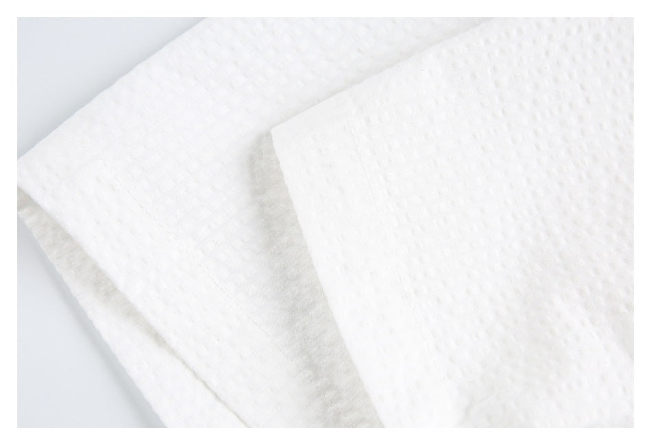 Close-up of folded white textured shirt fabric with a stitched edge.