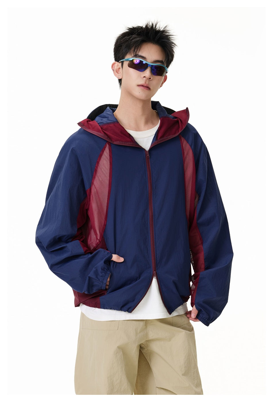 Front view of a model wearing a navy and burgundy color-block hooded jacket with mesh side panels.