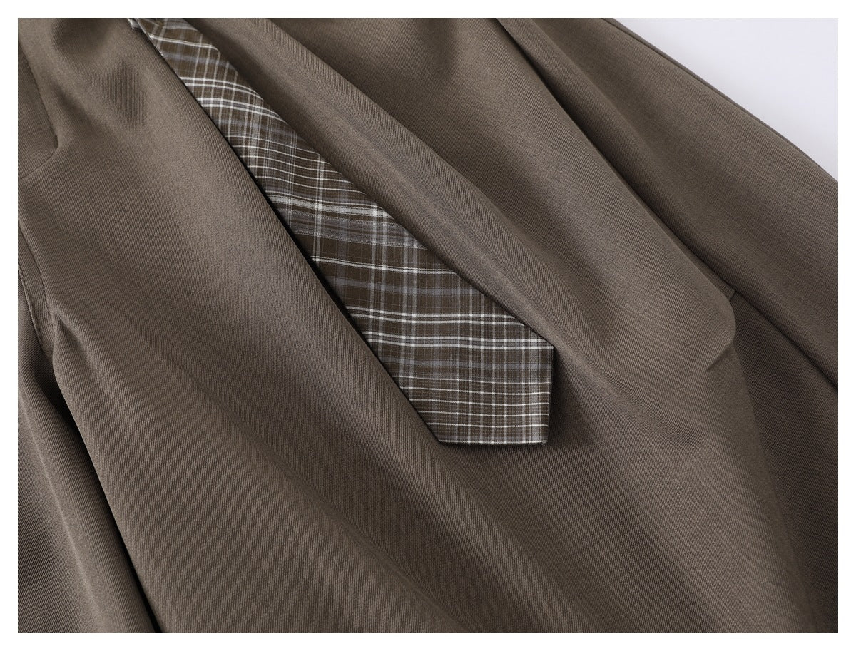 Close-up of taupe trousers with a brown-and-white plaid accent panel.