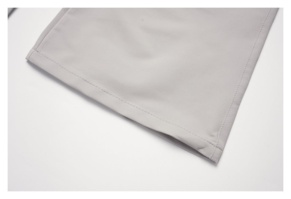 Close-up of the straight stitched hem on a light gray trouser leg.