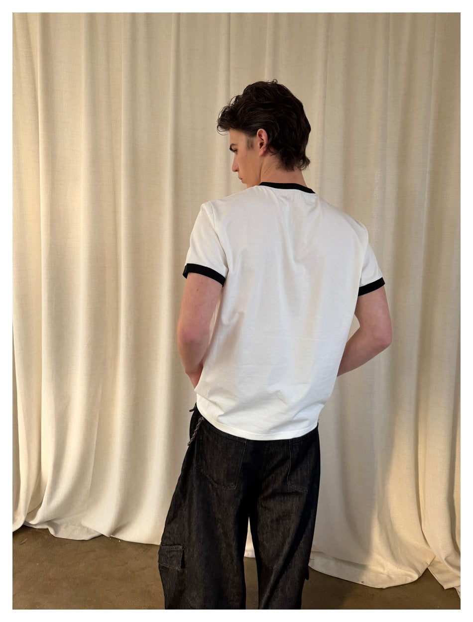 Rear view of a model wearing a white T-shirt with black neck and sleeve trim.