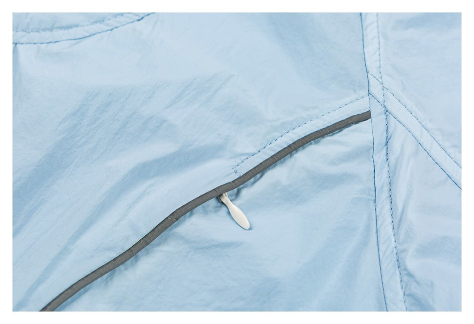 Close-up of a gray-edged seam and small white zipper pull on light blue fabric.