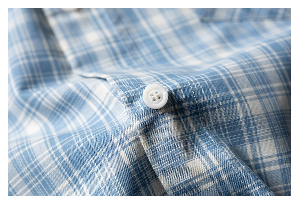 Close-up of a white button and stitched placket on a blue-and-white plaid shirt.