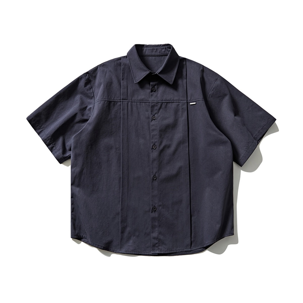 Navy short-sleeve button-up shirt with pleated front panel, chest seam and small metal tag, flat lay front view