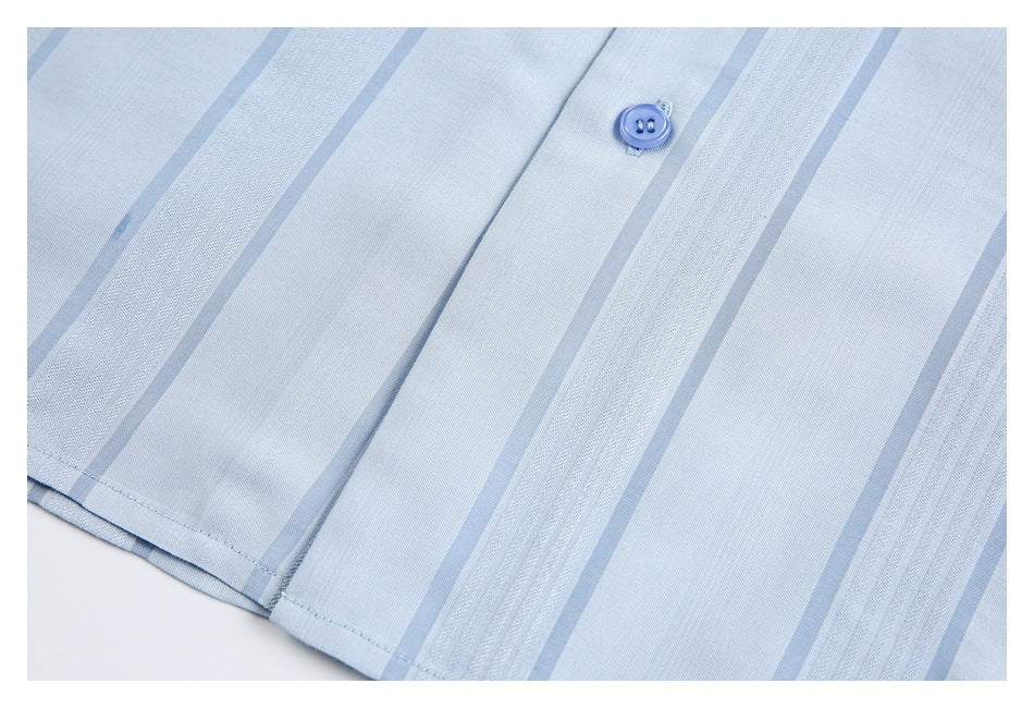 Close-up of the light blue striped shirt hem, seam, and a blue button.