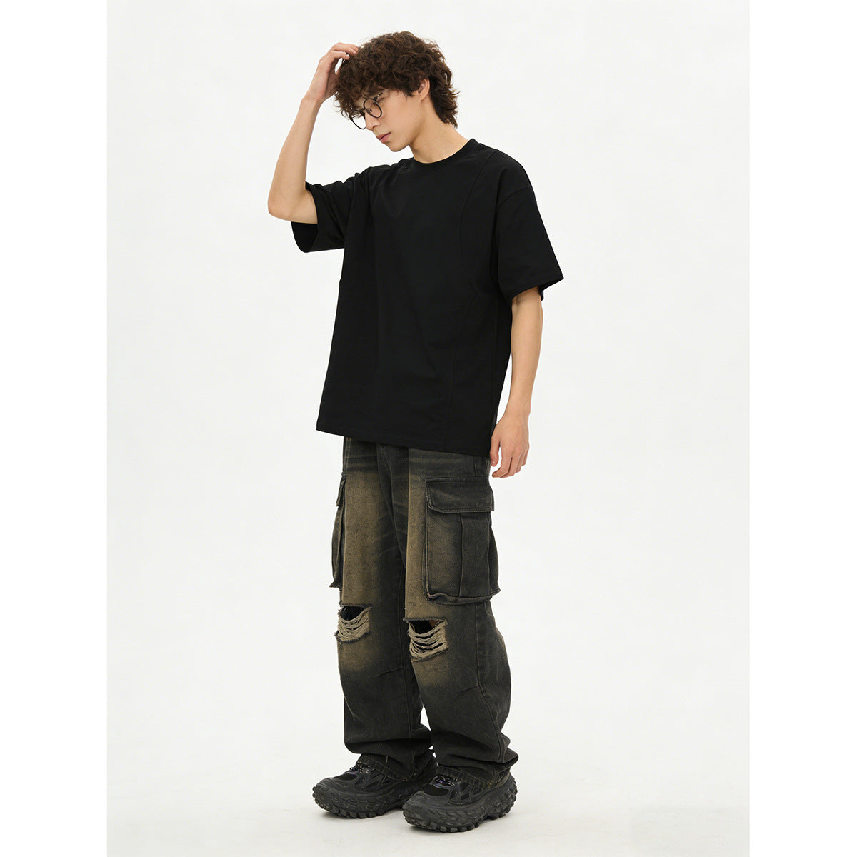 Model wearing an oversized black short-sleeve T-shirt with wide distressed cargo pants.