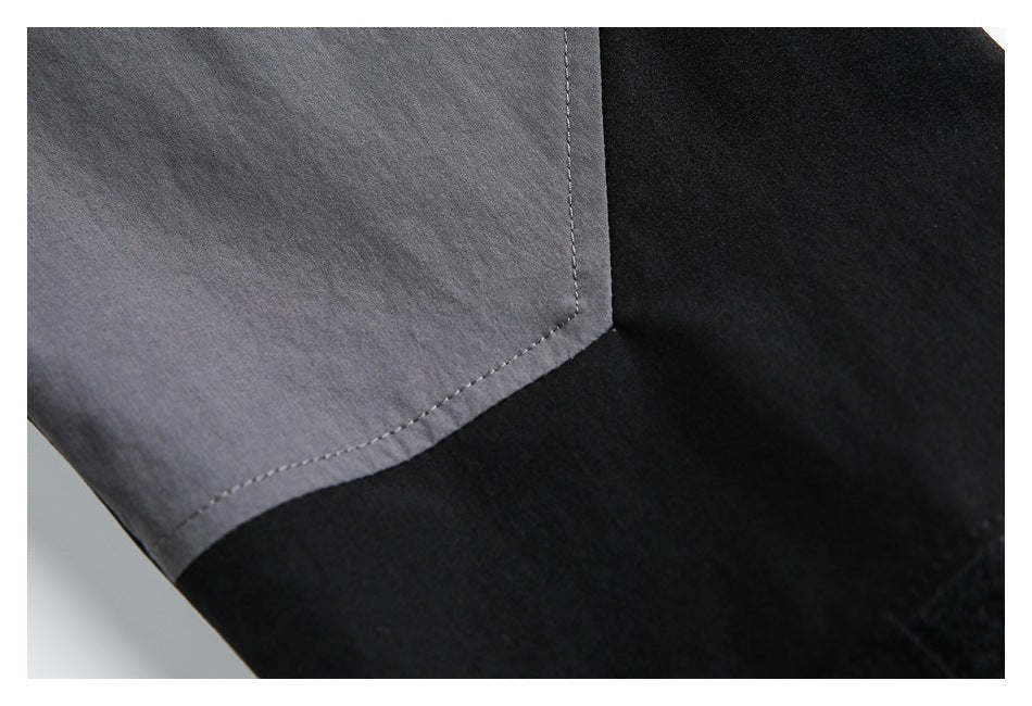Close-up showing a stitched charcoal-gray panel joined to black garment fabric.