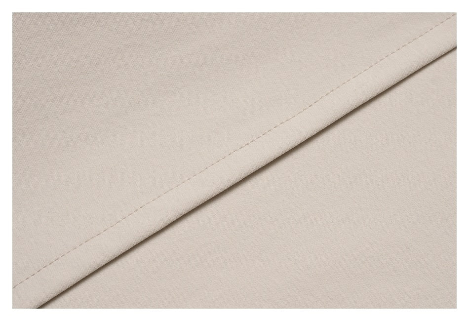 Close-up of light beige garment fabric with a diagonal stitched hem.