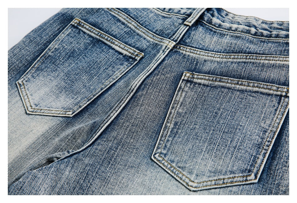 Close-up of blue faded denim jeans showing two rear pockets and contrast stitching.