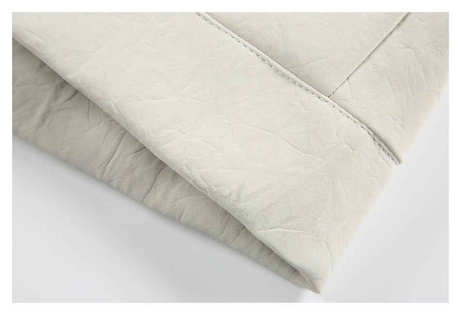 Close-up of the ivory jacket's folded lower edge and stitched seam.