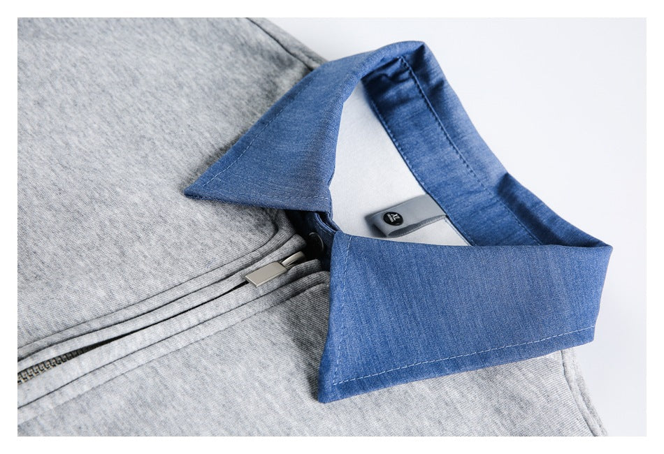 Close-up of the blue pointed collar and black button on a gray zip-up jacket.