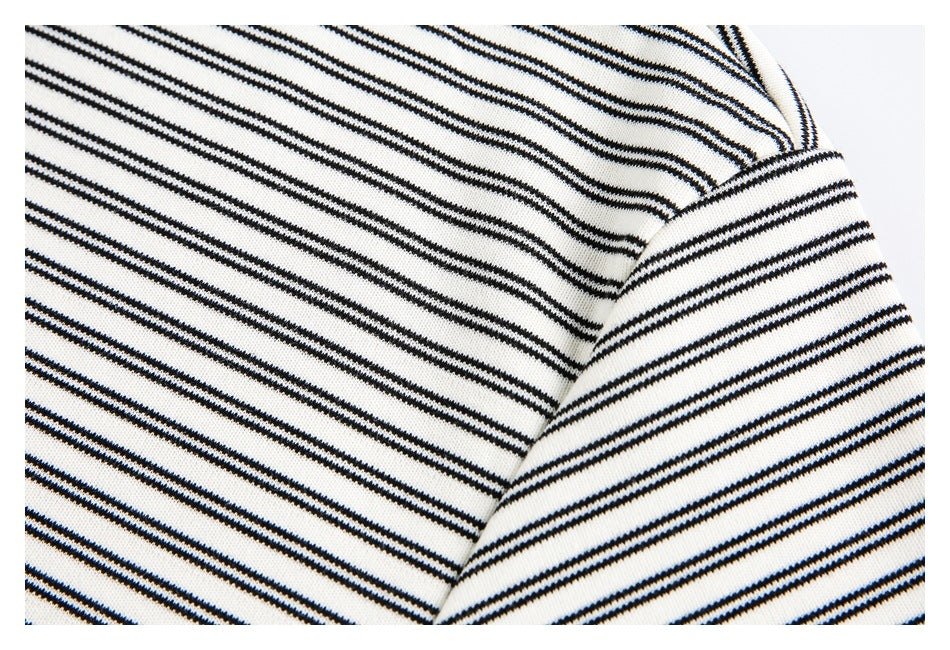 Close-up of an off-white garment with thin black stripes and a curved shoulder or sleeve seam.