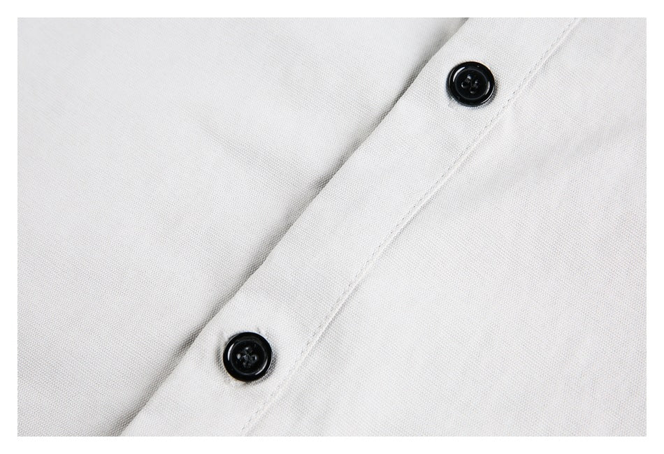 Close-up of two black buttons on the placket of a light-colored shirt.