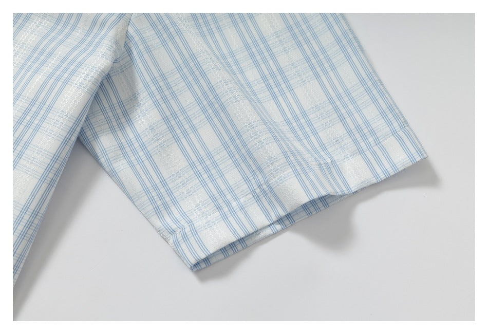 Close-up of a short sleeve hem on a white shirt with blue plaid and textured stripe details.