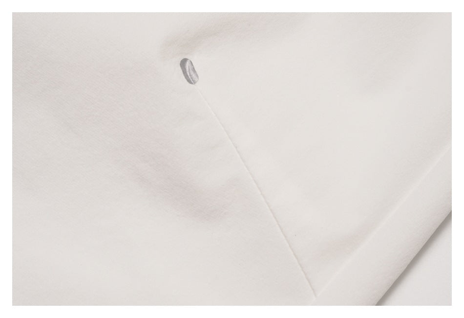 Close-up of white pant fabric with a seam and a small oval detail.