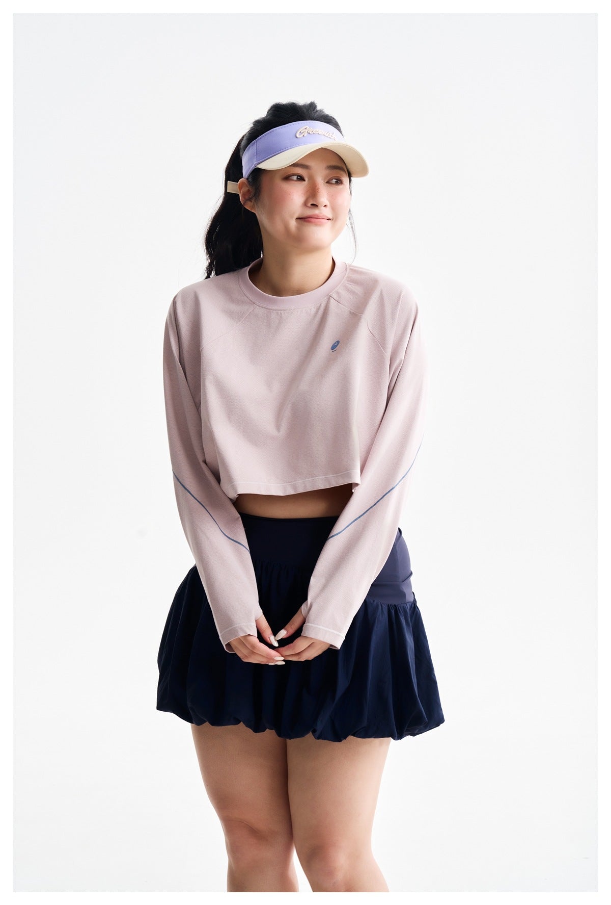 Model wearing a pale pink cropped long-sleeve top and navy bubble-hem skirt; the top has blue sleeve accents and a small
