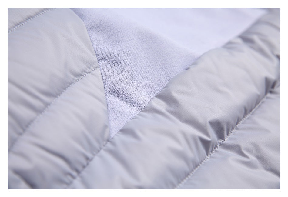 Close-up of a light gray textured knit panel joined to quilted fabric with visible stitching.