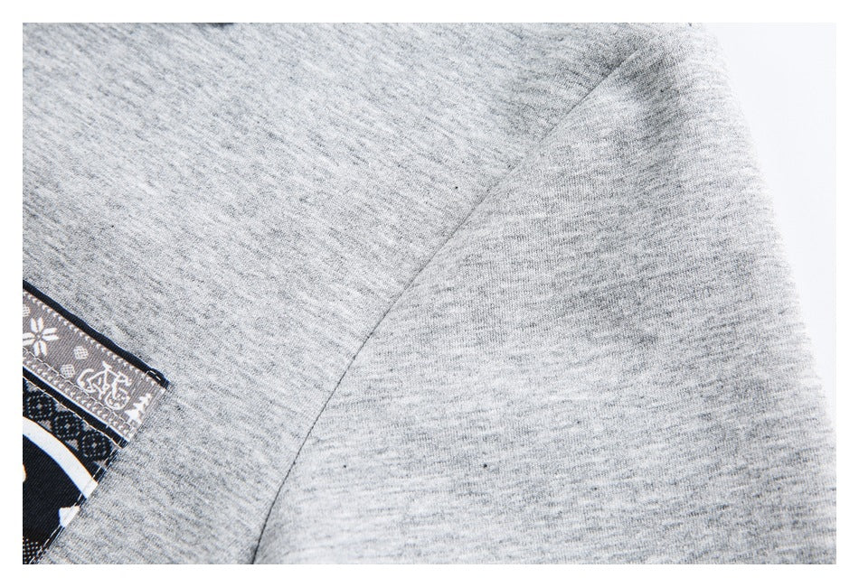 Close-up of a curved shoulder seam on light gray fabric, with part of a patterned pocket at the edge.