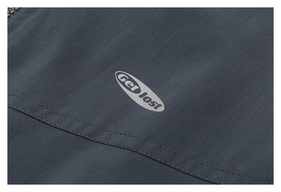 Close-up of a dark charcoal garment with a light oval “Get lost” print and curved stitching.