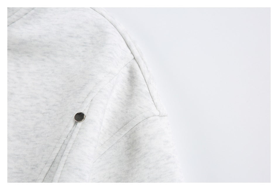 Close-up of a light gray heather garment with a small metal snap and curved stitched seam.