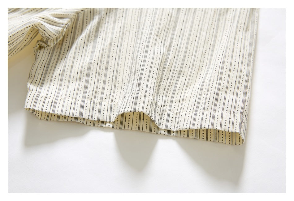 Close-up of the striped garment's hem, showing its folded edge against a white background.