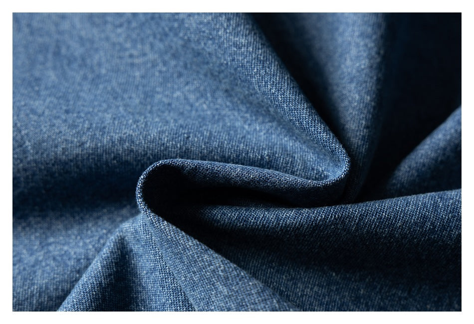 Macro close-up of blue denim fabric gathered into folds, showing its weave and texture.