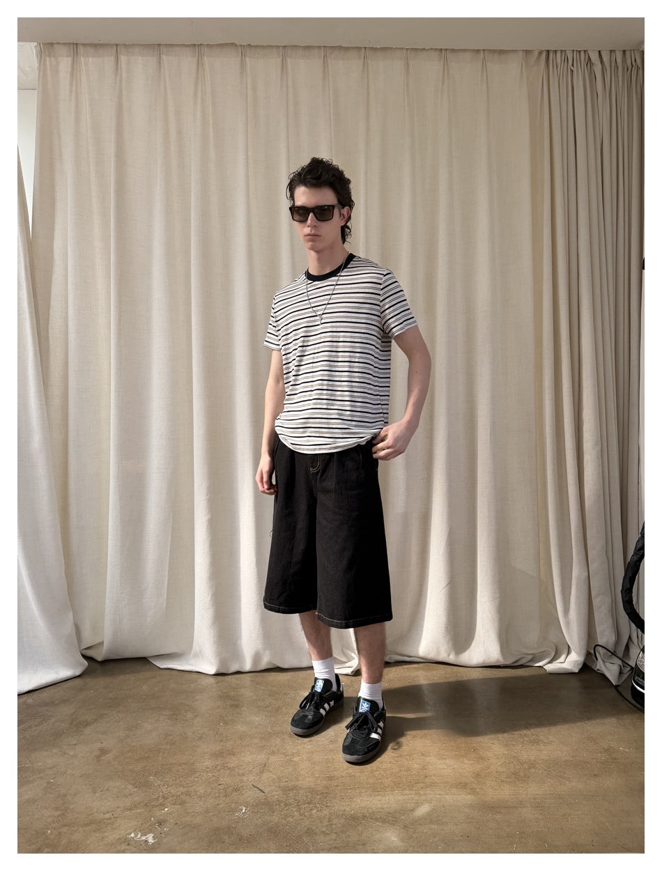 Model wearing a white and dark striped short-sleeve T-shirt with loose black shorts, shown at a slight angle.