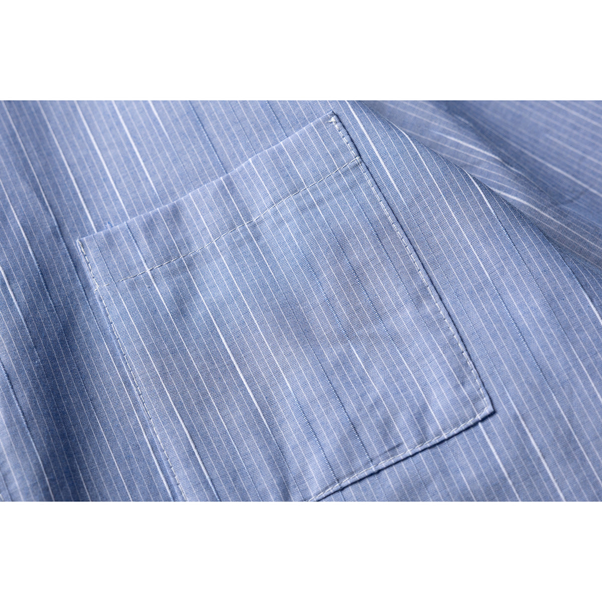 Close-up of a rectangular chest pocket on blue-and-white pinstriped shirt fabric.