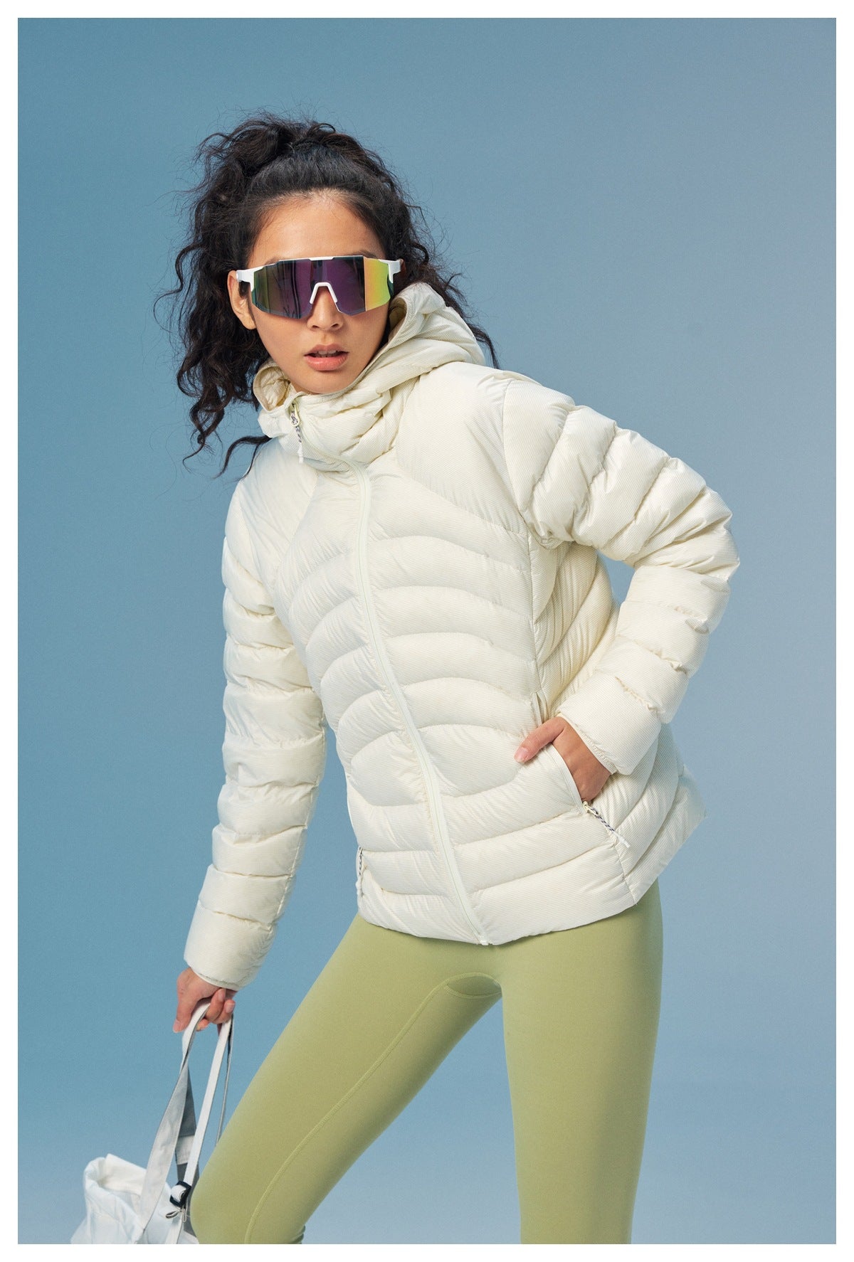 Model wearing a white quilted puffer jacket with a high collar and pale green leggings.