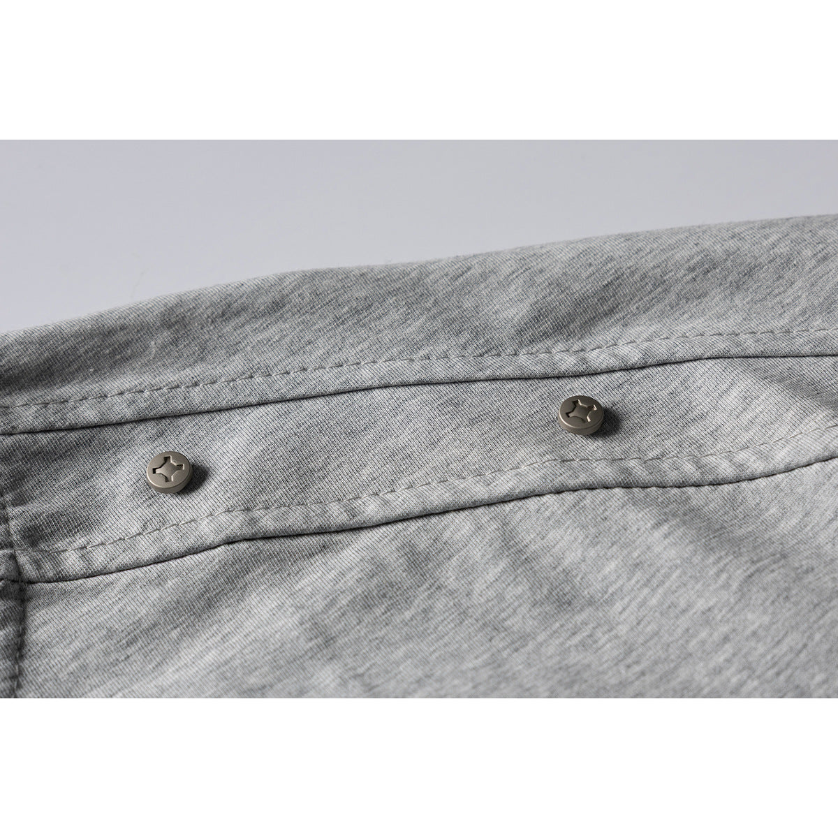 Close-up of two dark buttons on a gray T-shirt shoulder tab.