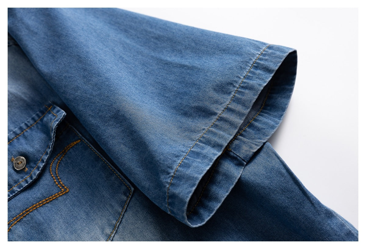 Close-up of a blue denim shirt sleeve opening and stitched edge beside the chest pocket.