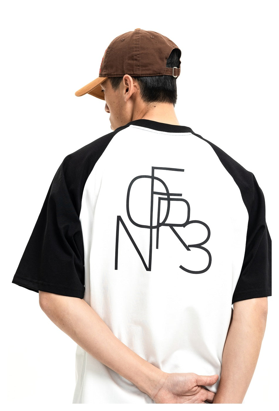 Rear view of a white raglan T-shirt with black sleeves and a large black graphic across the back.
