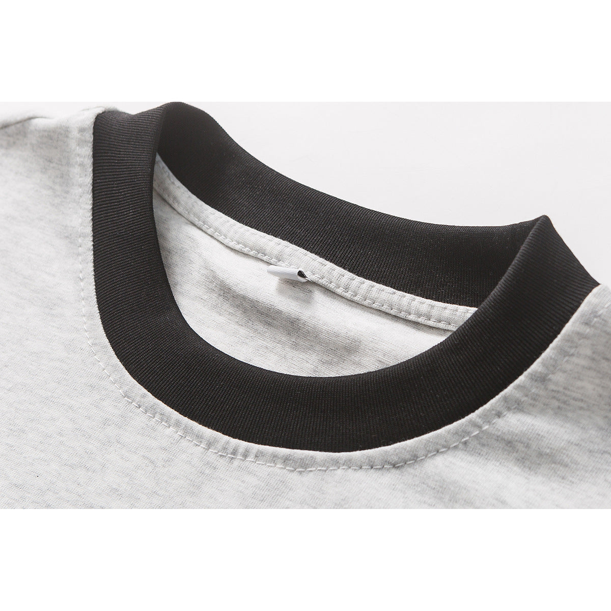 Close-up of a light gray T-shirt with a wide black ribbed crew neck and visible collar stitching.