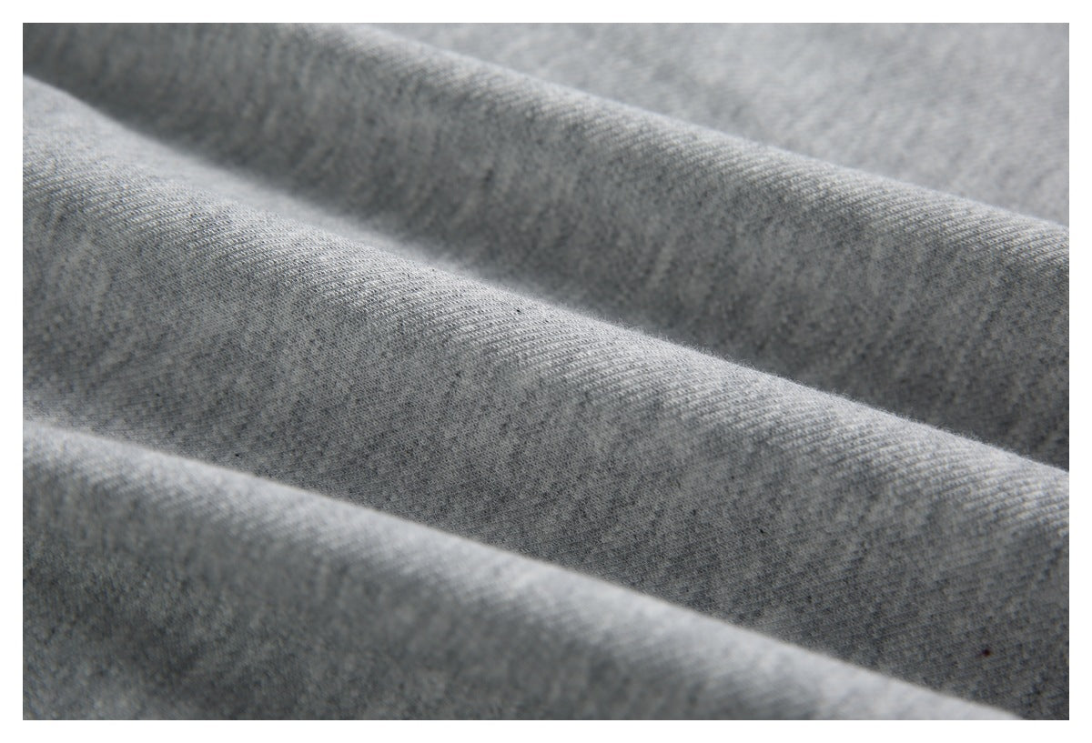 Close-up of gray knit fabric arranged in soft diagonal folds, showing its fine textured surface.