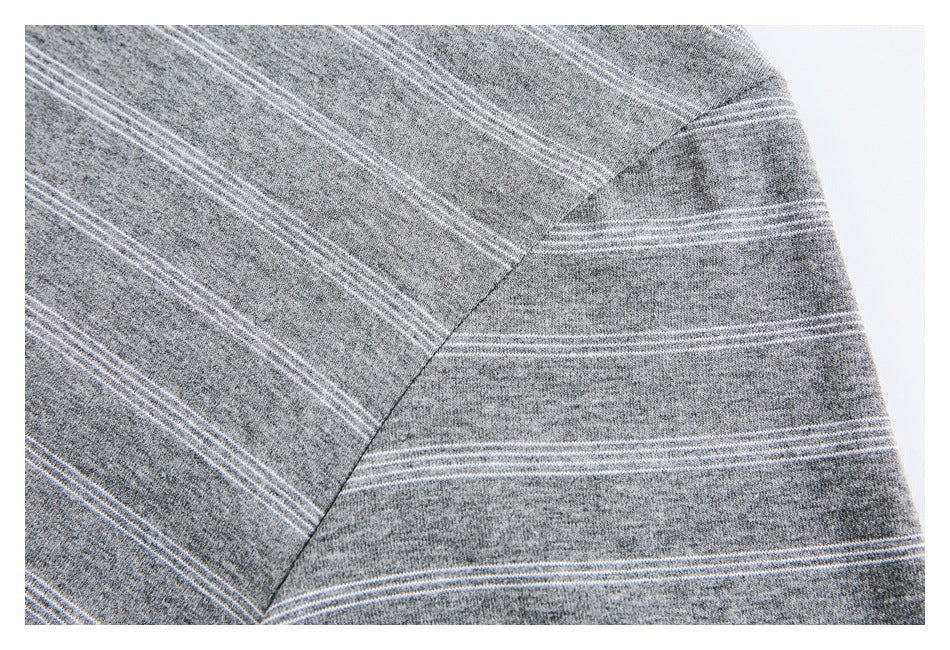 Close-up of the shoulder seam and striped sleeve of a gray shirt.