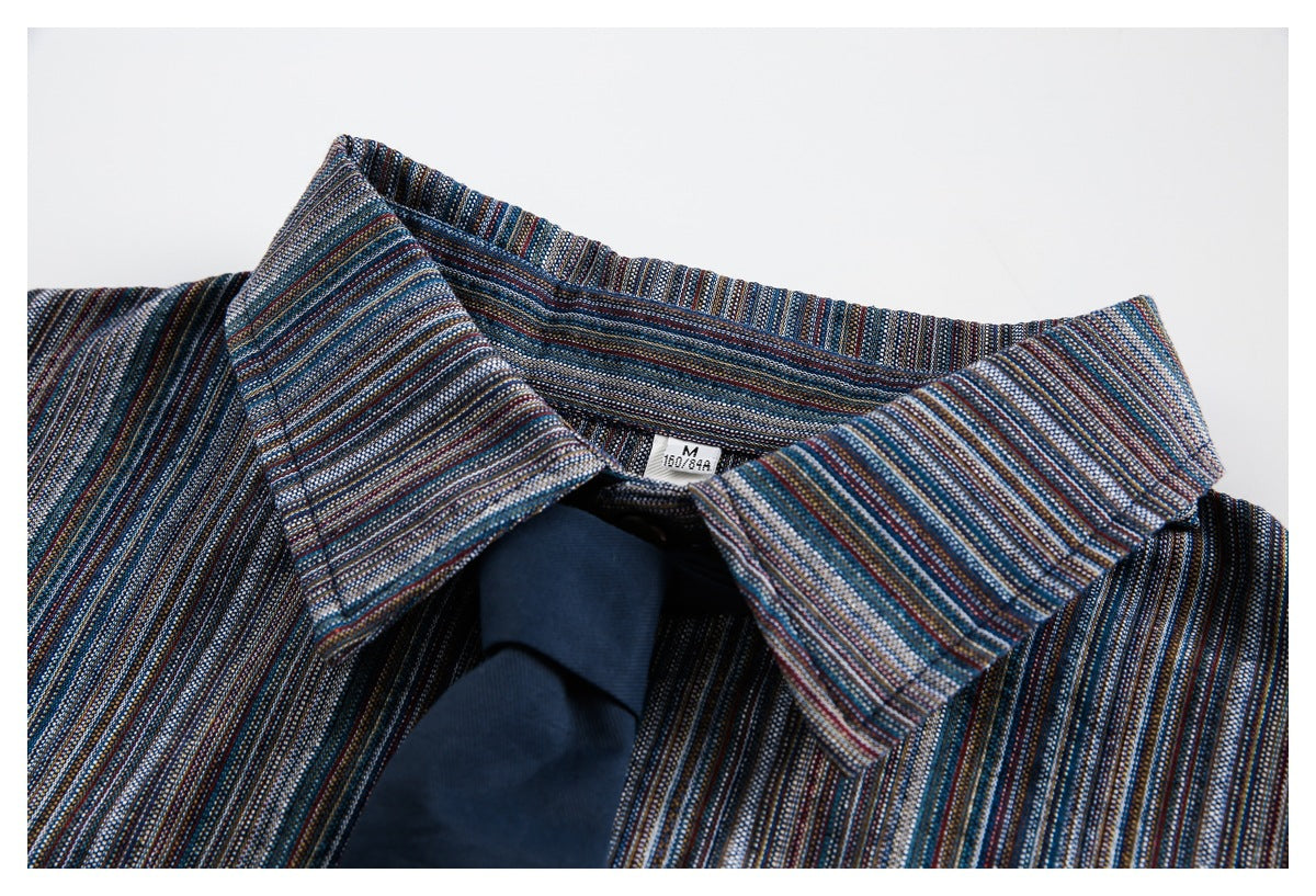 Close-up of a pointed collar on a dark blue multicolor-striped shirt.