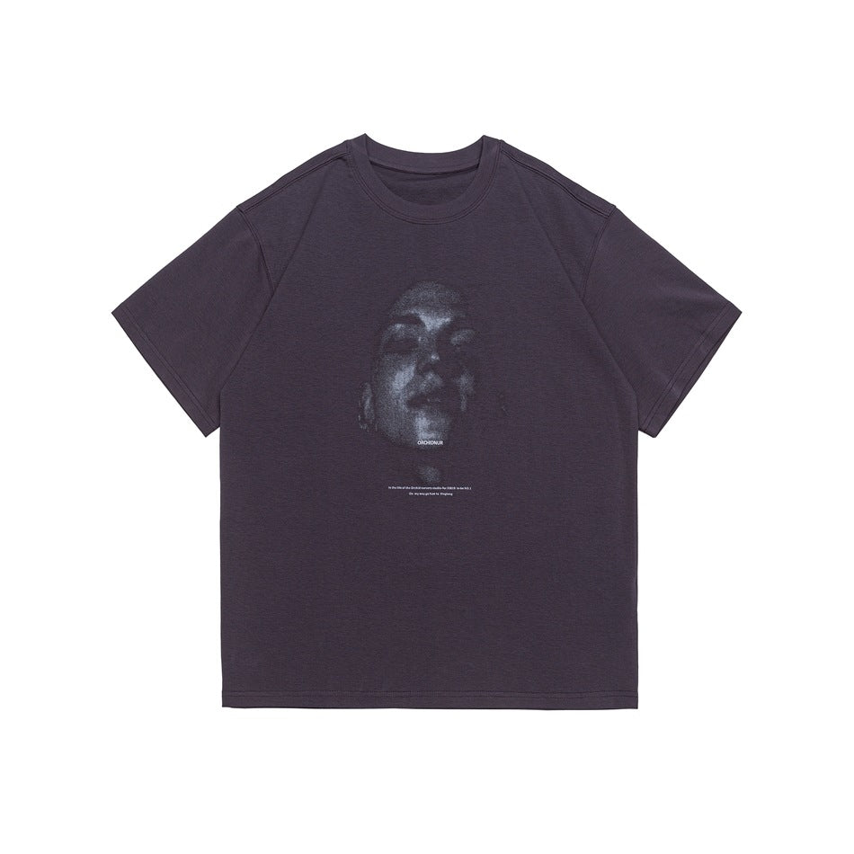 Purple short-sleeve crewneck T-shirt with a grainy face portrait graphic and small text print on the chest