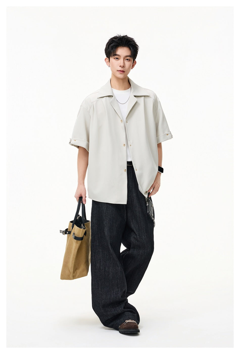 Full-length model wearing a light cream oversized short-sleeve shirt with wide lapels and rolled cuffs.