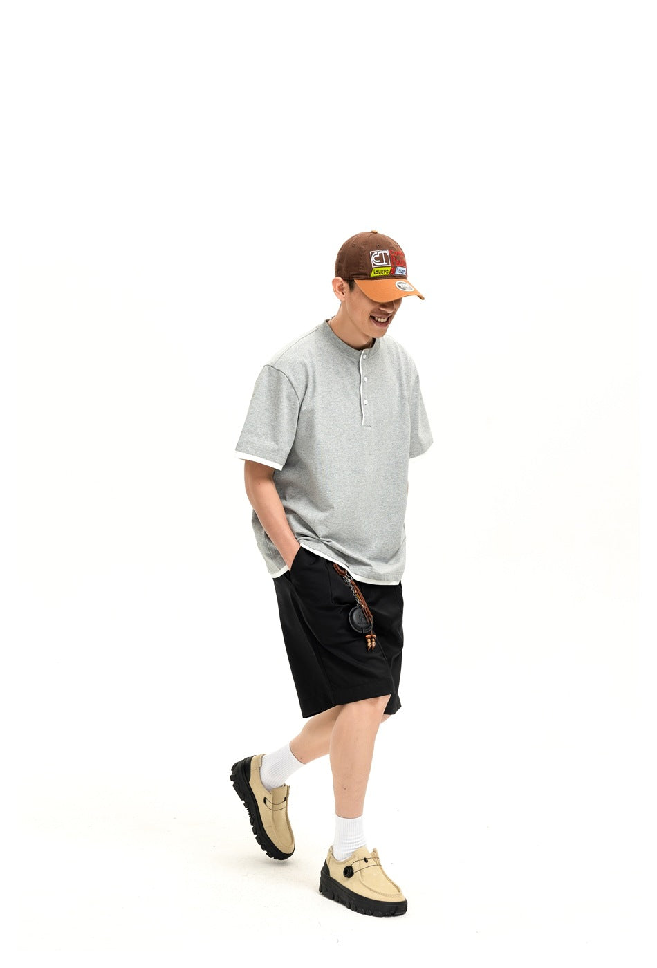 Person wearing a light gray short-sleeve henley shirt with white trim and black shorts, shown in a walking pose.