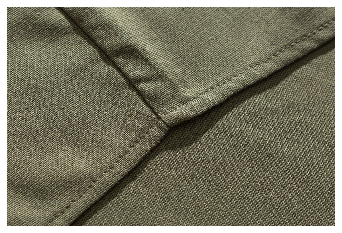 Close-up of olive green woven fabric showing a folded edge and diagonal seam stitching.