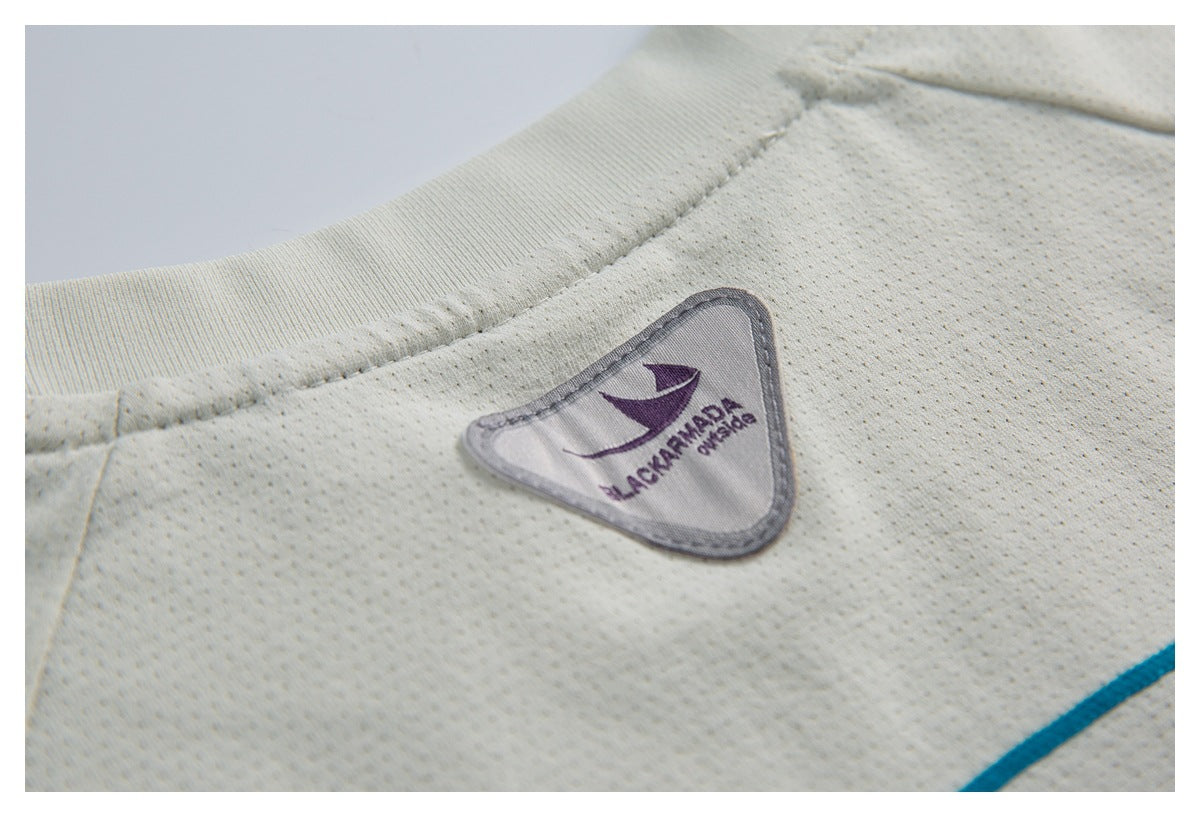 Close-up of an ivory perforated garment showing its ribbed neckline and purple logo patch.