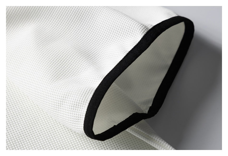 Close-up of a white textured fabric opening finished with black binding.