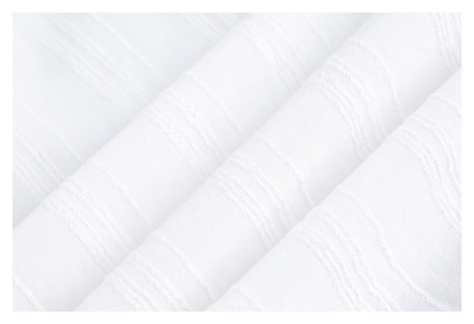 Close-up of white fabric showing raised stripe texture in soft folds.
