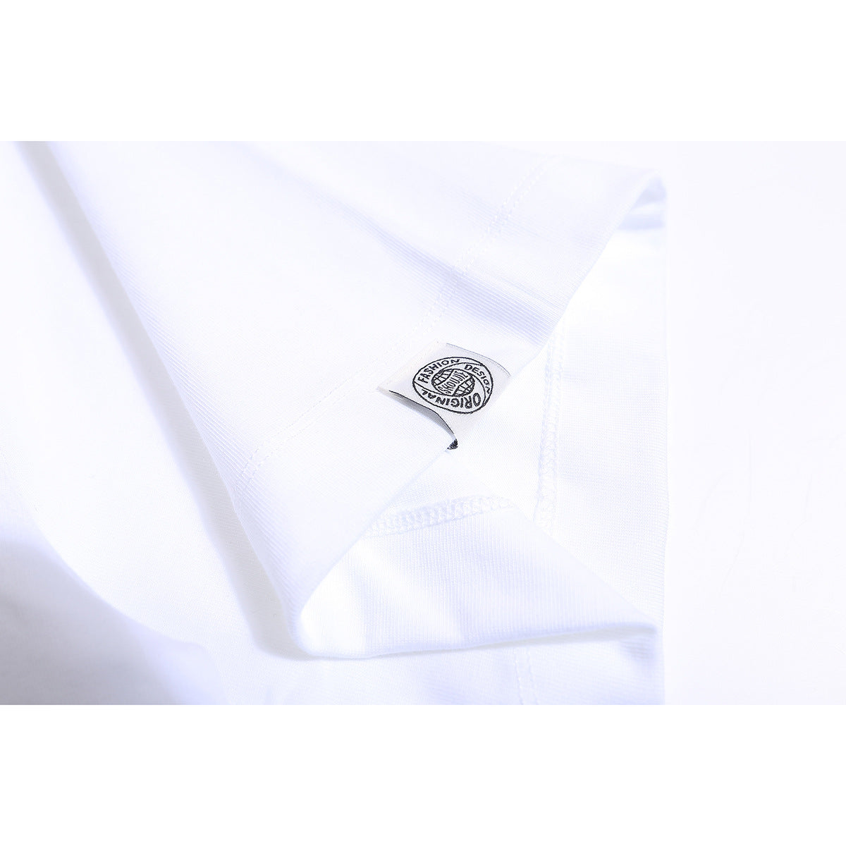 Close-up of a small sewn label and overlocked seams on a white T-shirt.
