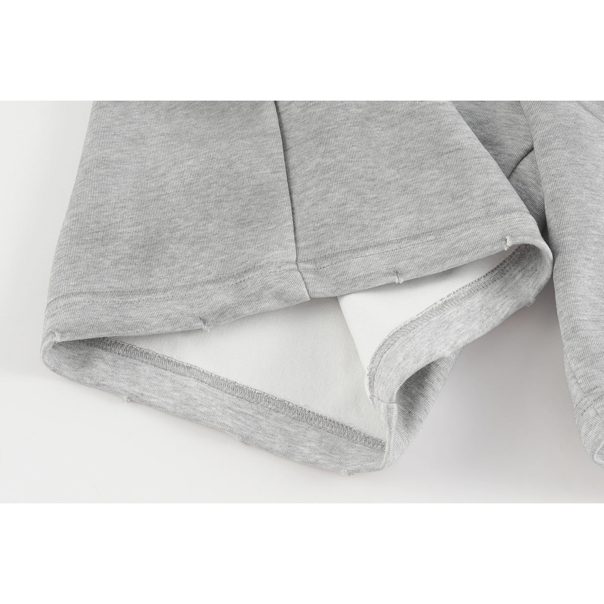 Close-up of a light gray shorts leg hem with visible stitching and the inner side of the fabric.