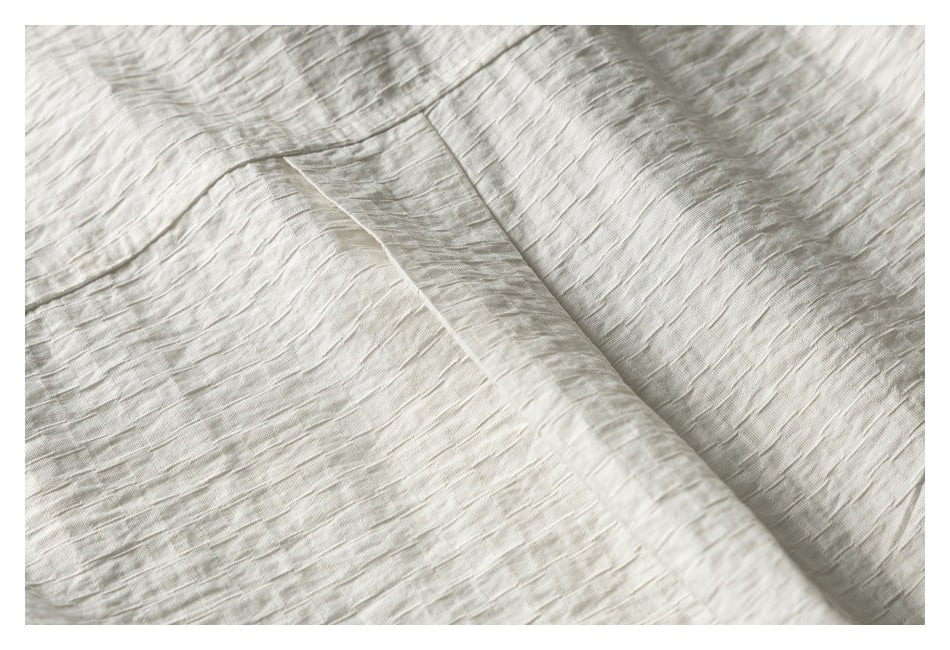 Close-up of ivory fabric showing a fine slubbed texture and overlapping folded edges.
